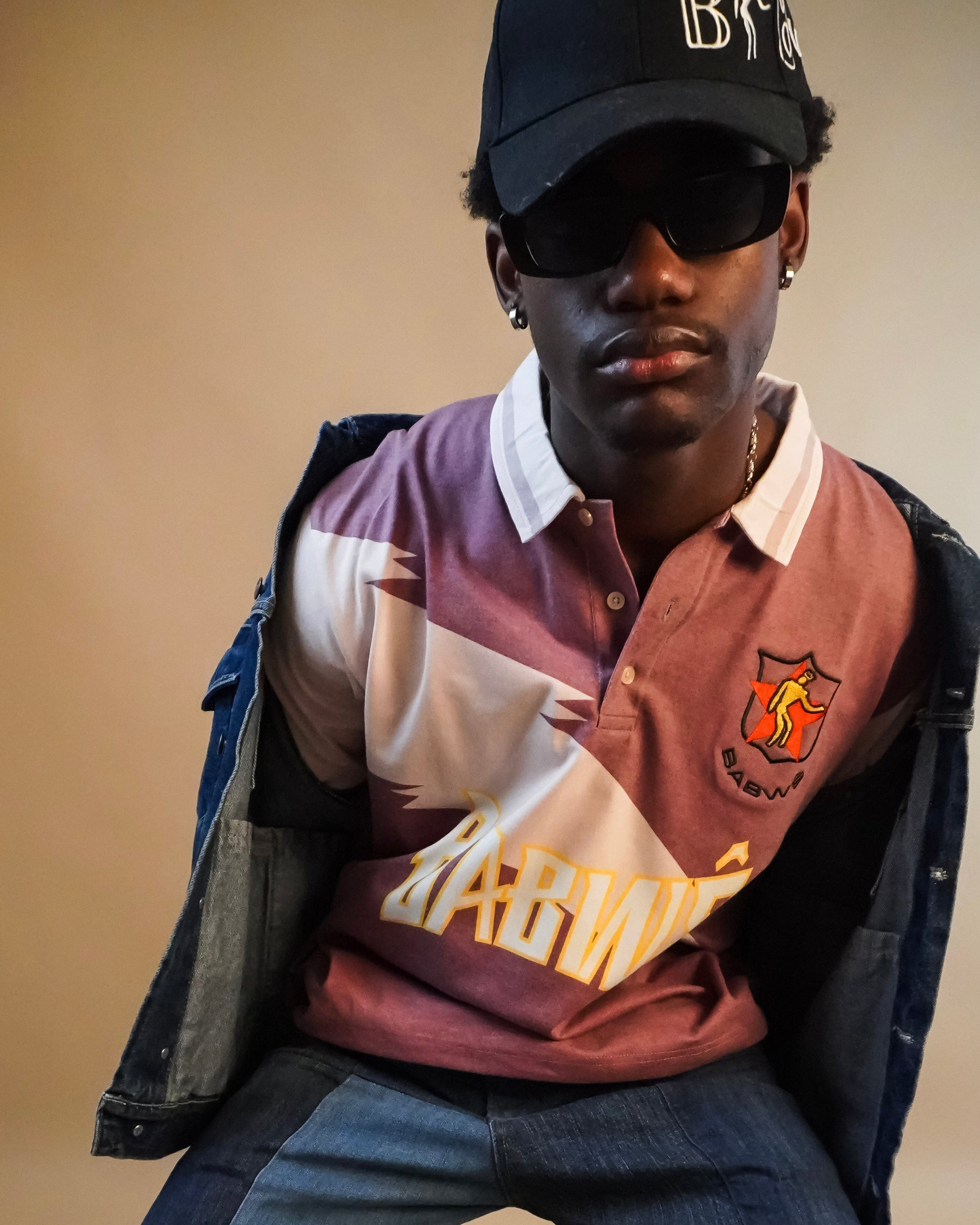 Person wearing a cap and colorful vintage, Zimbabwean cricket t-shirt against beige background