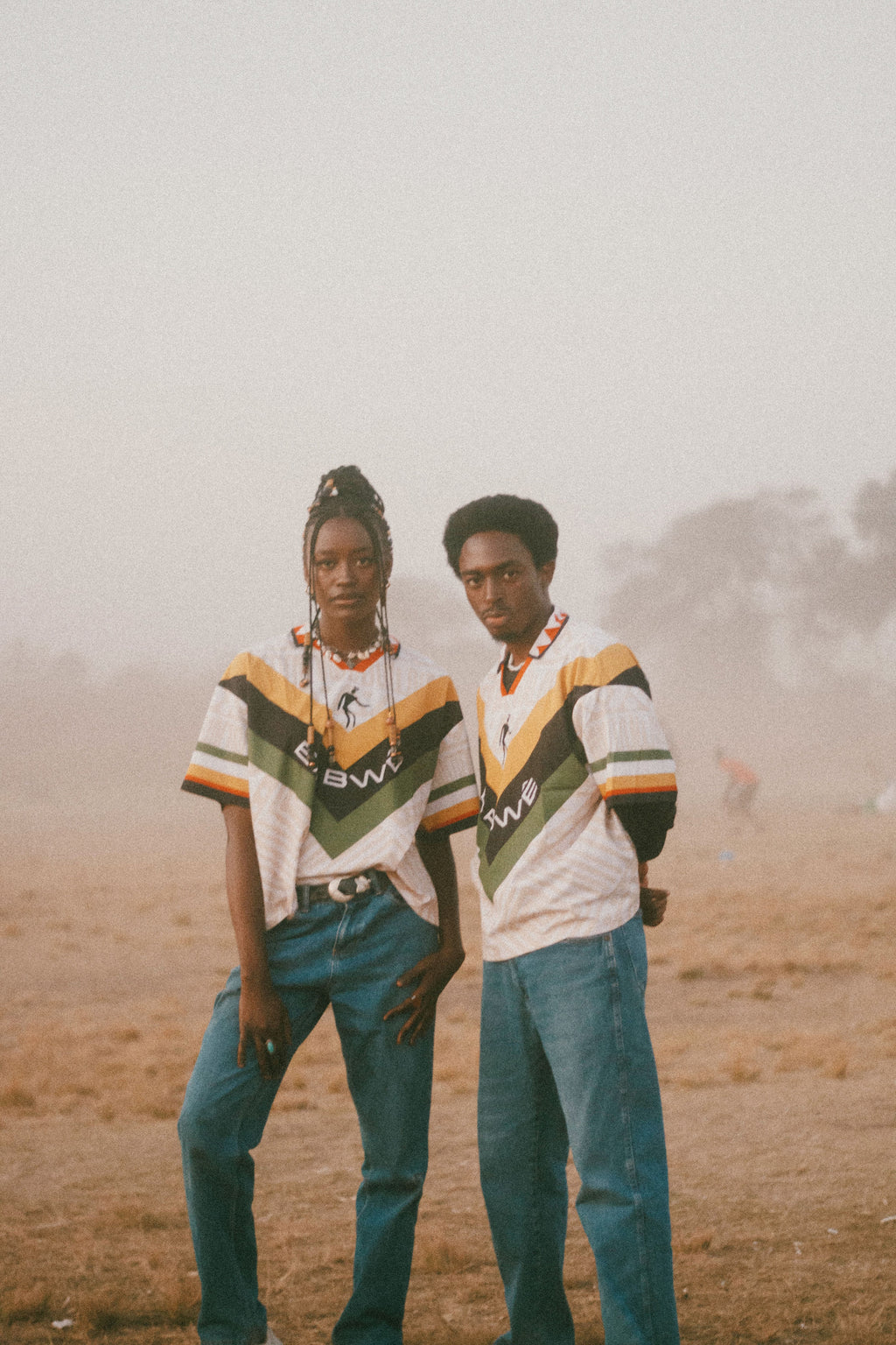 Two people wearing matching Babwê vintage Zimbabwe soccer jersey – nostalgic 90s design blending African streetwear with national pride in a misty outdoor setting